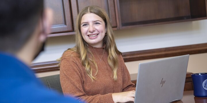 Student smiling and working at a computer