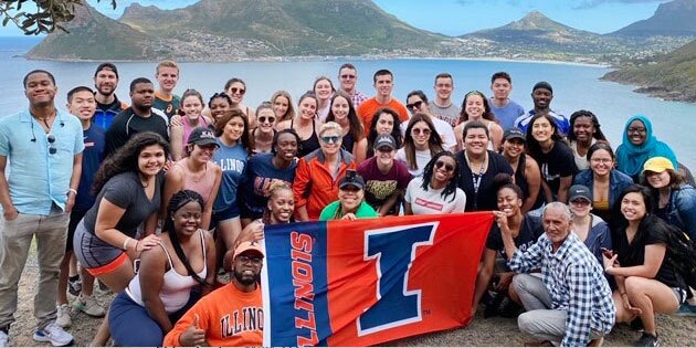 Students abroad holding up a University of Illinois flag.