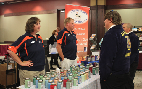 Joyce and Brad Riskedal stand behind candle booth and talk to customers