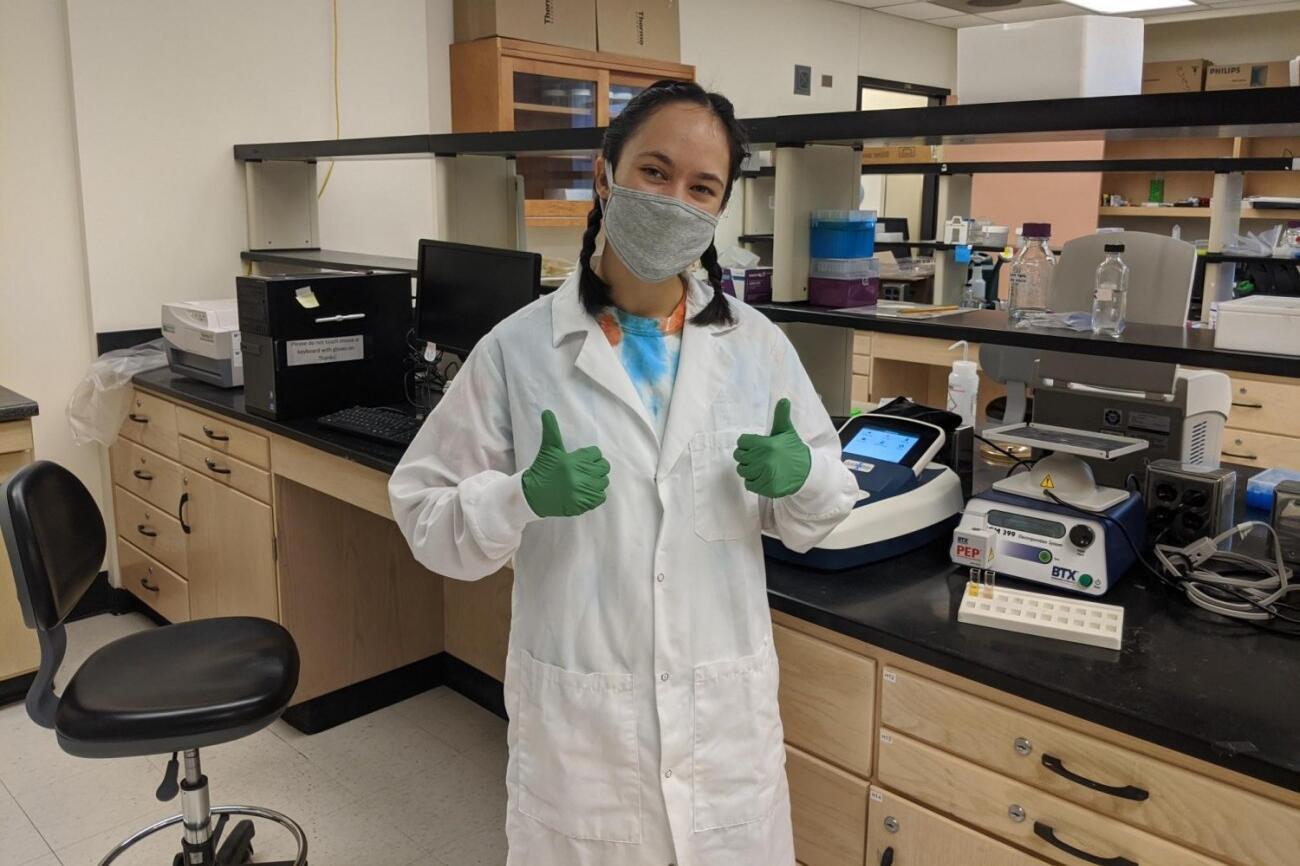 student in laboratory giving thumbs up