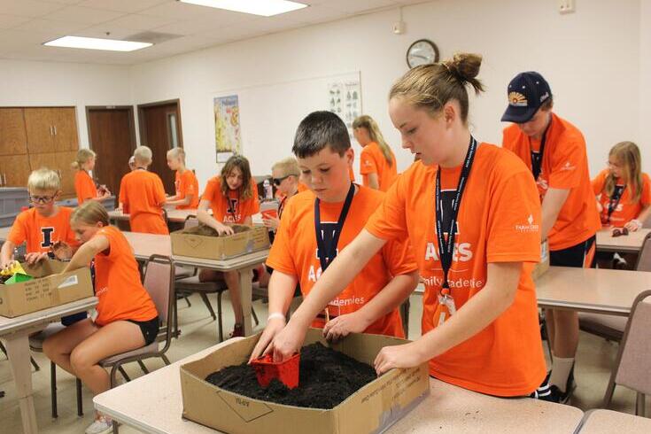 A group of students attending ACES Family Academies dig in different boxes of soil as part of activity.