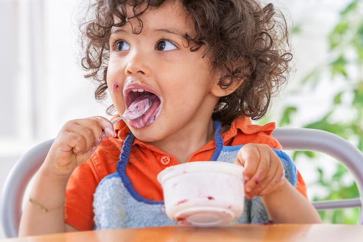 Toddler eating yogurt from container