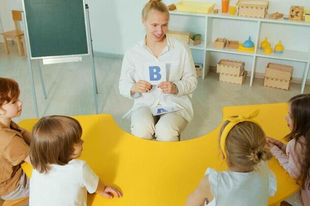 A teacher holds a card with the letter b for her students to read