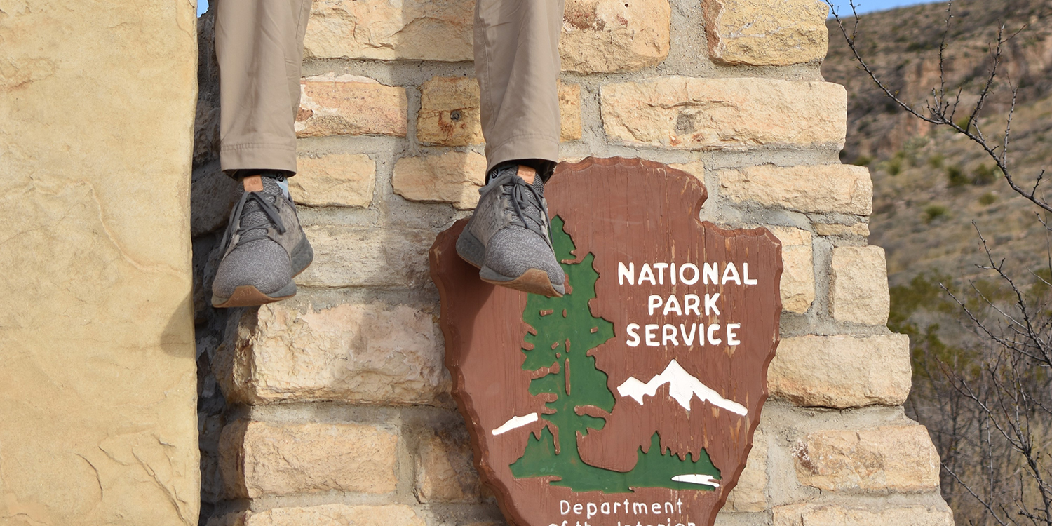 Alex Brockamp's feet dangling in front of a National Park Service sign