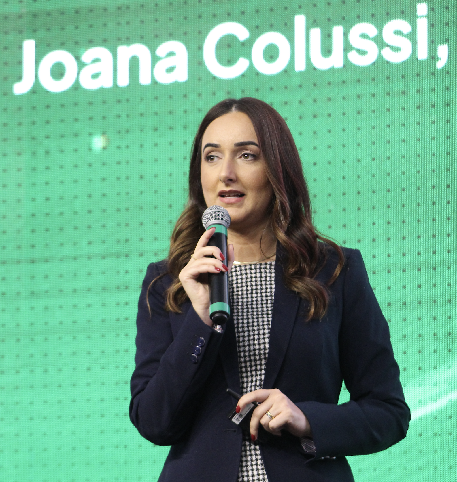 Joana Colossi standing with a microphone pointed towards her mouth