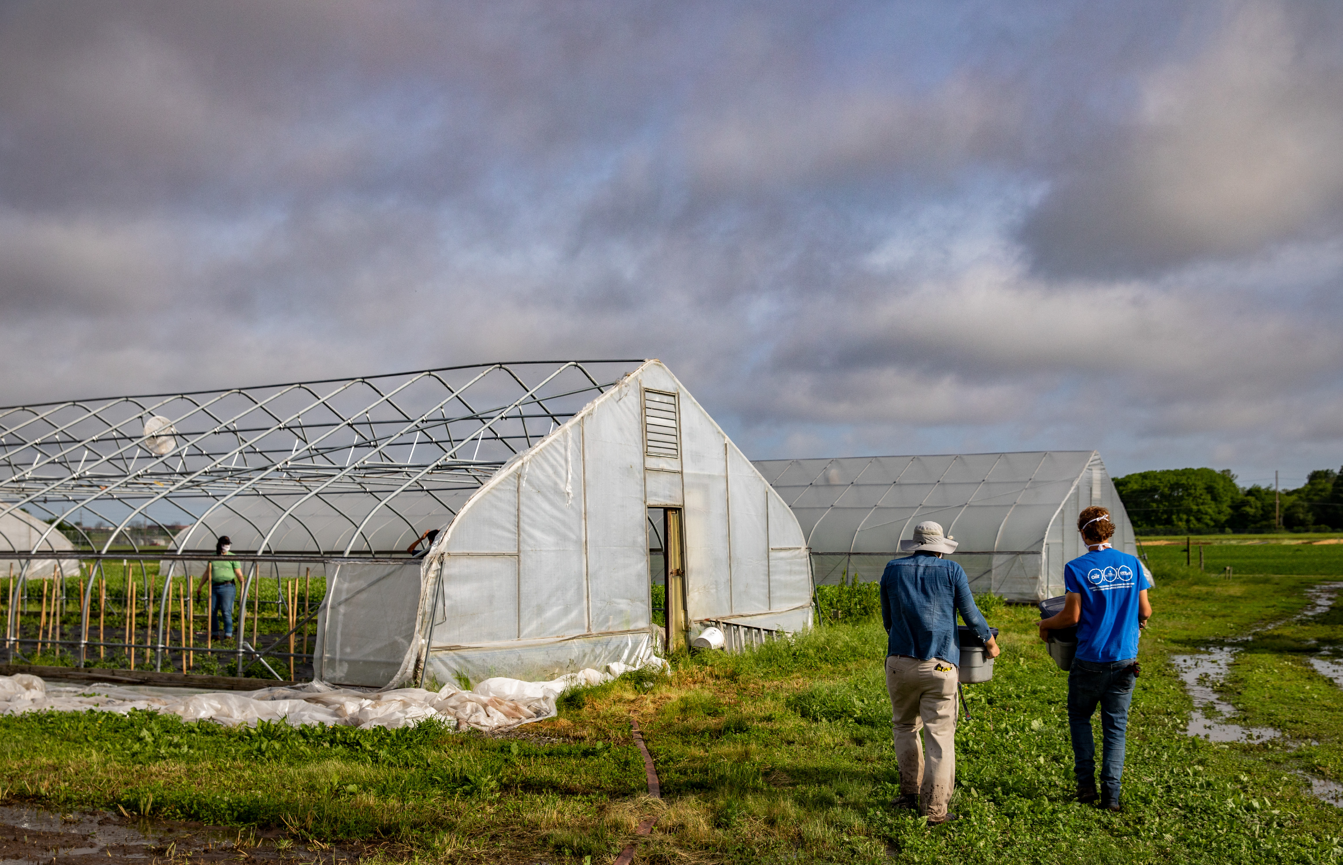 Two people stand outside the greenhouse at the Sustainable Student Farm