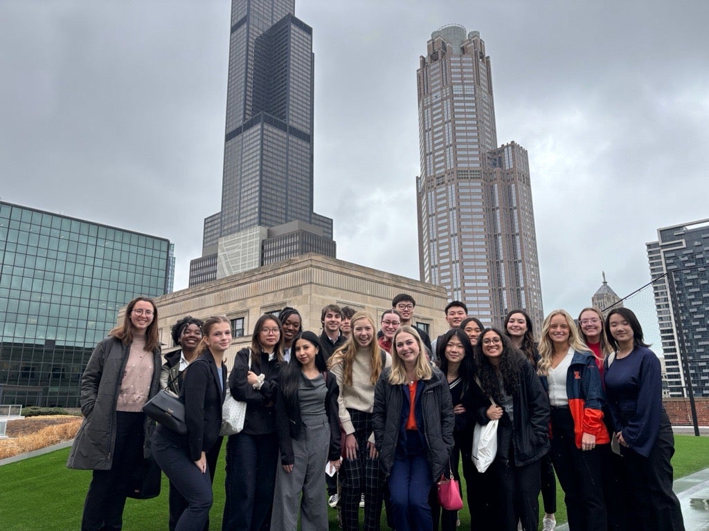 A group of students pose on a rooftop with Chicago skyscrapers visible in the background