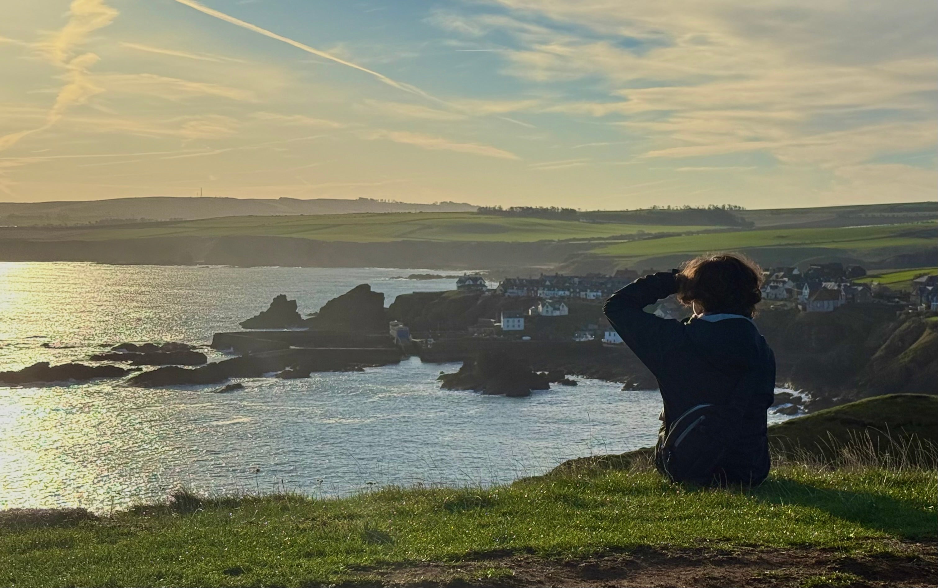 Landscape in Scotland with a student on the right-hand side, sitting with their back to us