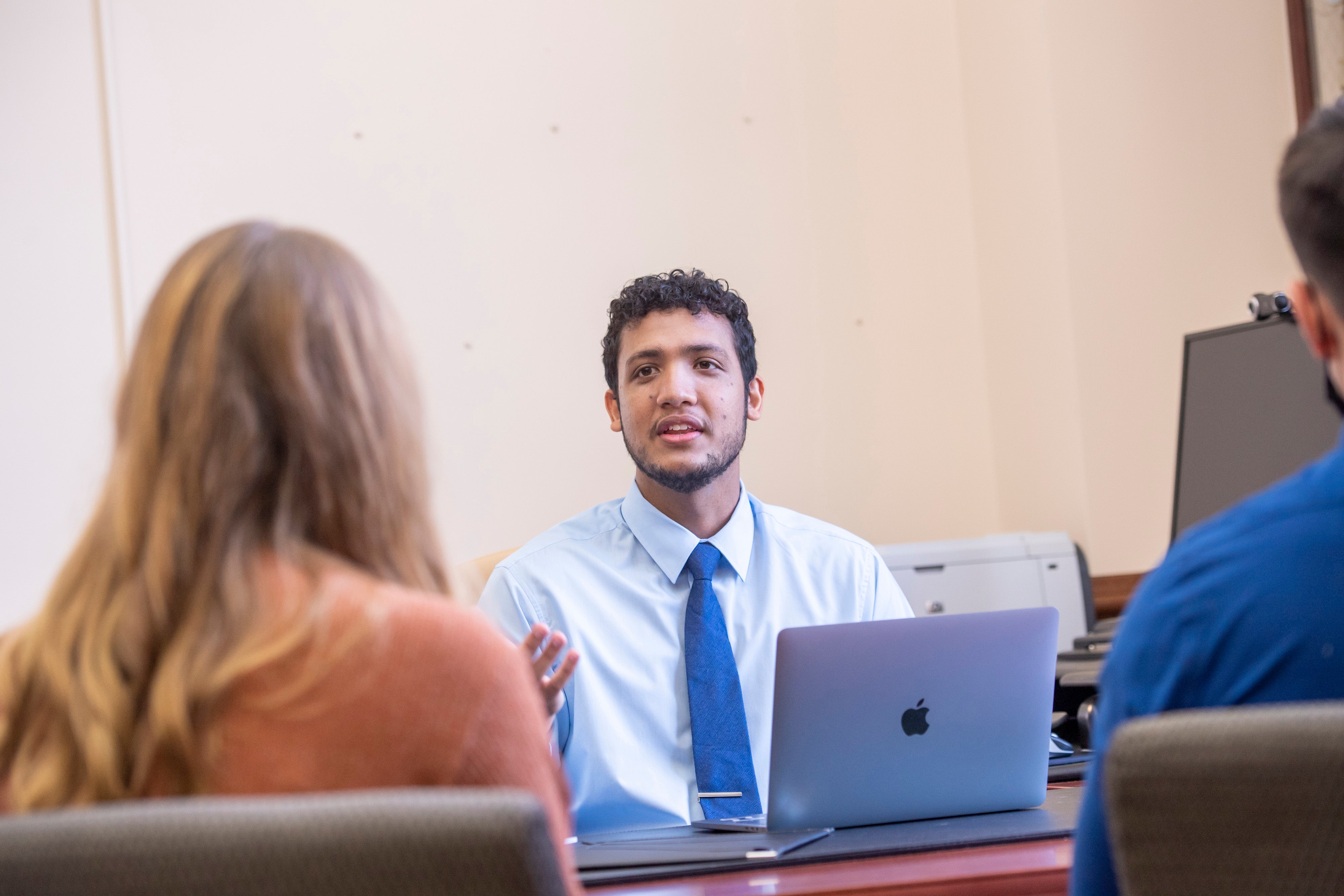 Financial planning student sitting at a table speaking with other students