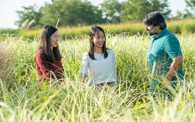 Students speaking with a professor in a field