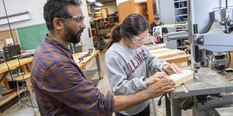 Student using a saw with the help of a professor