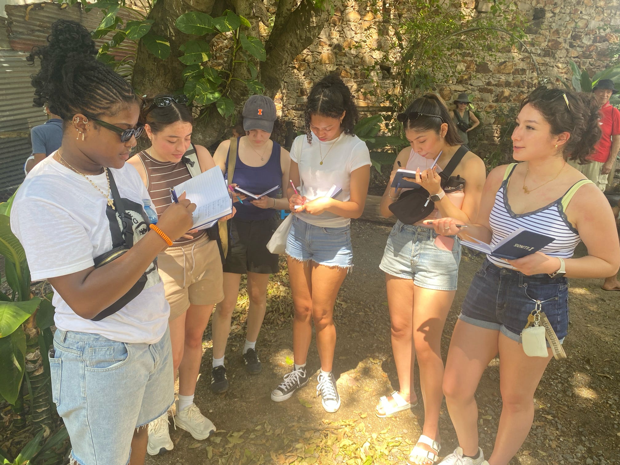 Students standing in a semi-circle and writing in journals in Panama