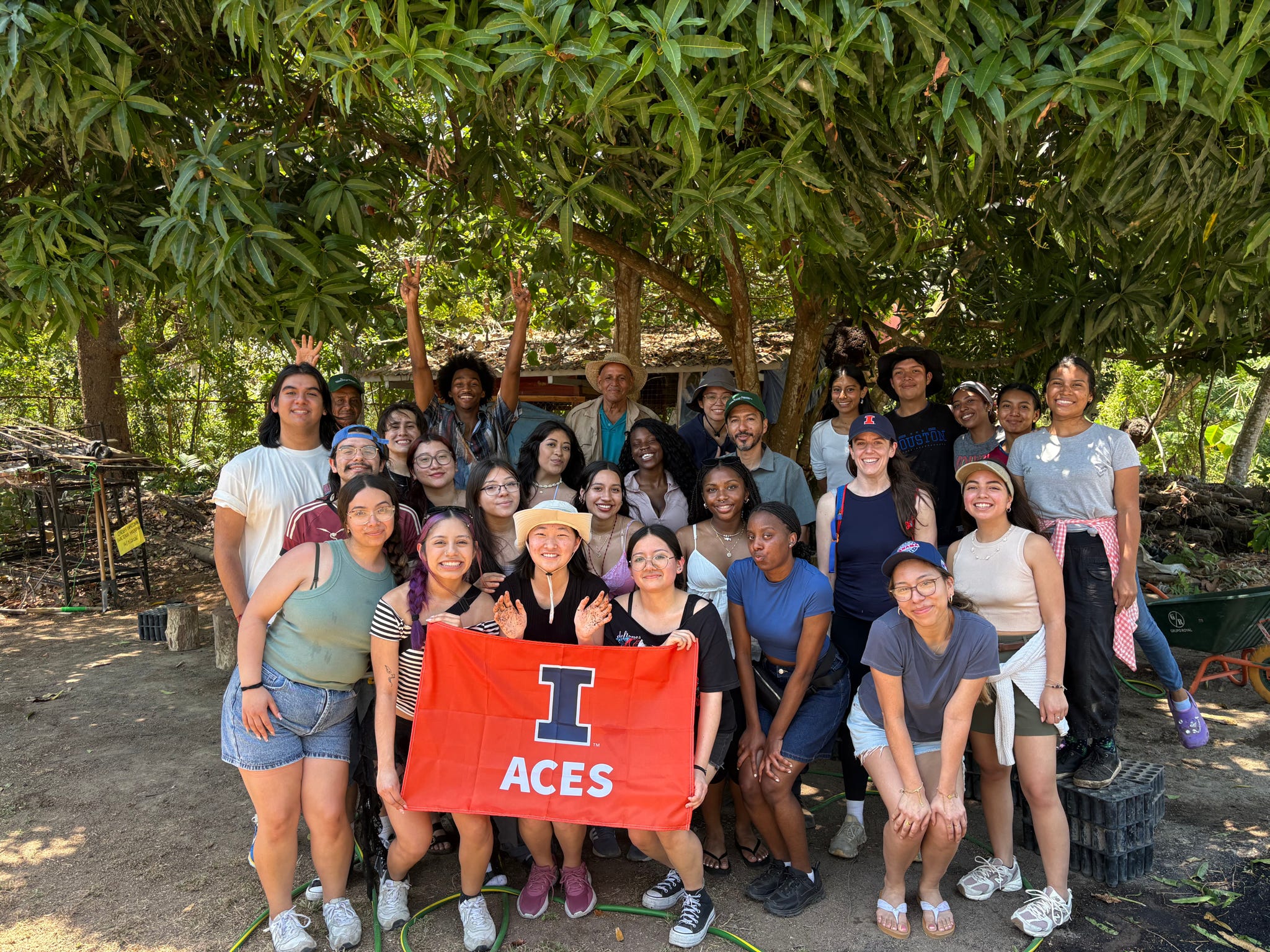 Group of students in Panama under a tree holding the ACES flag