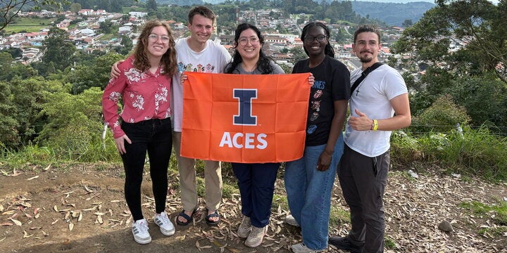 Four students holding the ACES flag on top of a hill in the Quindio region of Colombia