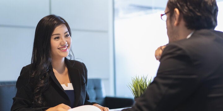 Two people having a conversation at a table in a professional setting.