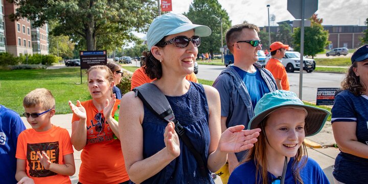 Family standing outside watching a parade.