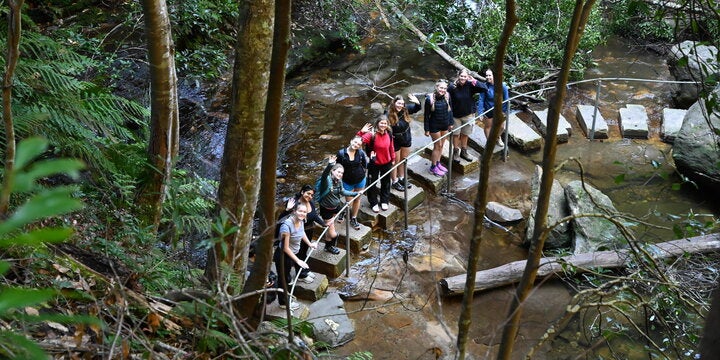 Students waving from bridge in river