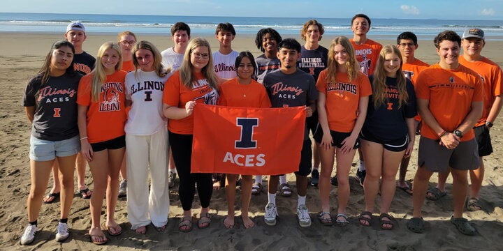 Group of students on the beach in Panama with an ACES flag