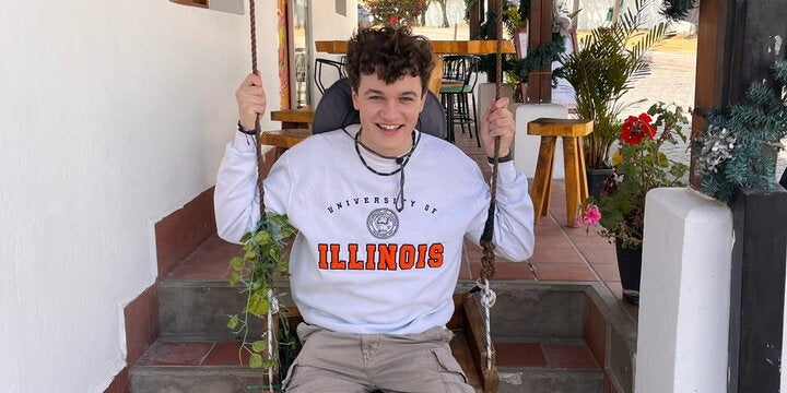 Student with an Illinois sweatshirt on a swing in Ecuador