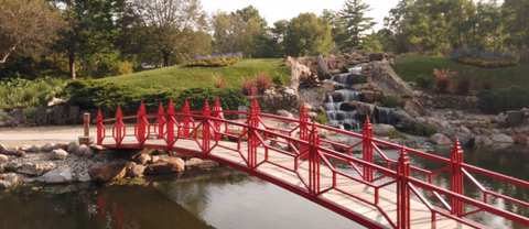 Red bridge next to a rocky waterfall.