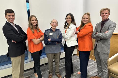 Five students stand with Jim Evans, their arms crossed. 