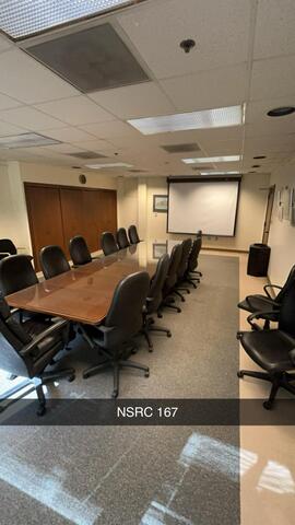 A conference room, labeled "NSRC 167," features a long polished table surrounded by large black chairs, with a projector screen at the front of the room.