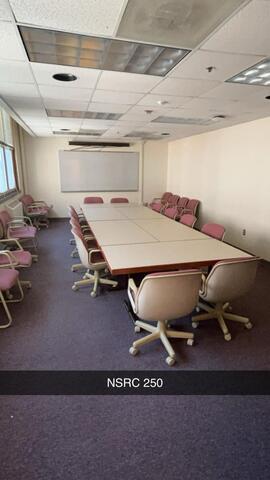 A small conference room, labeled "NSRC 250," is arranged with a rectangular table surrounded by pink chairs, additional seating along the walls, and a whiteboard at the front of the room.