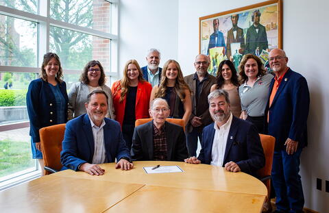 Dr. Jim Evans gathers with a group for the ceremonial signing. 