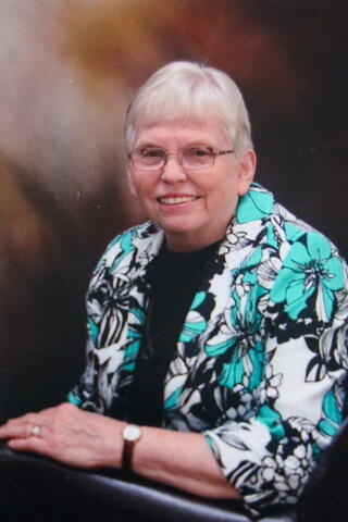 A headshot of Beatrice H. Bagby in a blue, black and white floral top.
