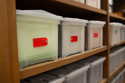 Labeled plastic totes line a set of shelves