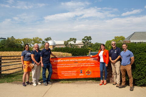 Six leaders from ACES and Bayer stand beside the Morrow Plots. 