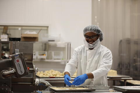 A man stands in the pilot plants and lays cookies out on a sheet