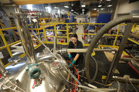 A woman works in a large facility with multiple pieces of laboratory equipment