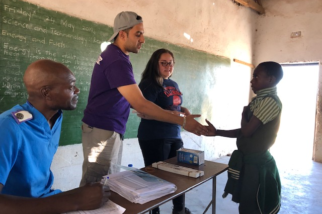 Shoeb Ahmed interacting with a student in a classroom with chalkboard in the background