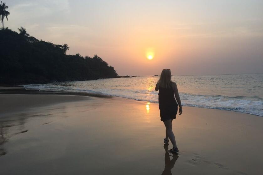 Riley Maloney walking away from camera on the beach at sunset