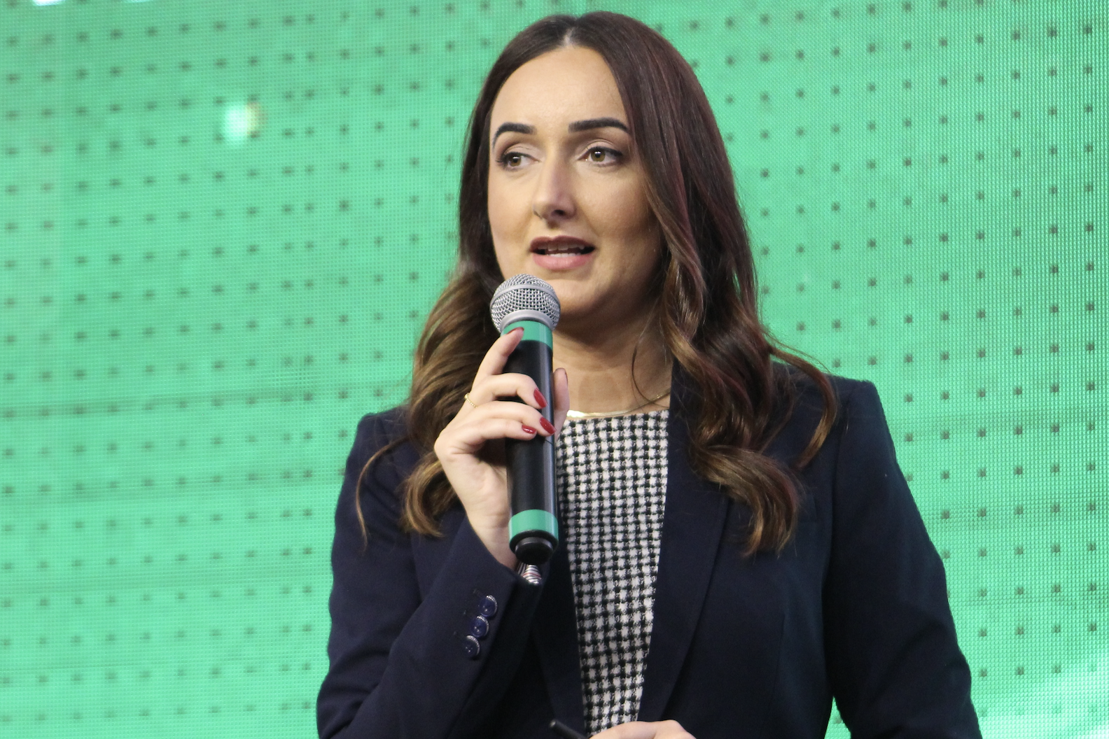 Joana Colossi standing with a microphone pointed towards her mouth