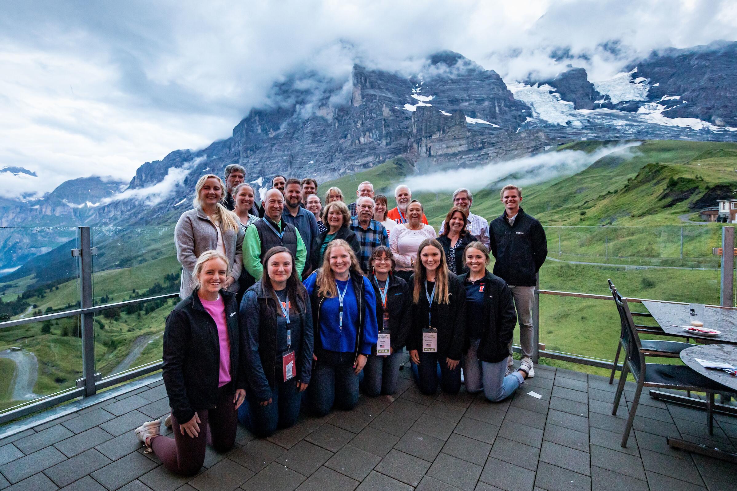 A large group gathered together with mountains in the background. 