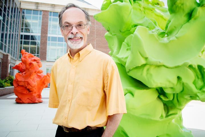 Gustavo Caetano-Anolles stands next to a lime green statue. 