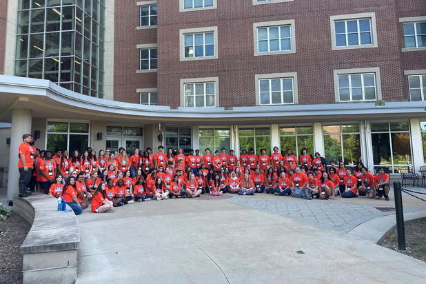 Illini Summer Academies participants sit in front of a brick building.