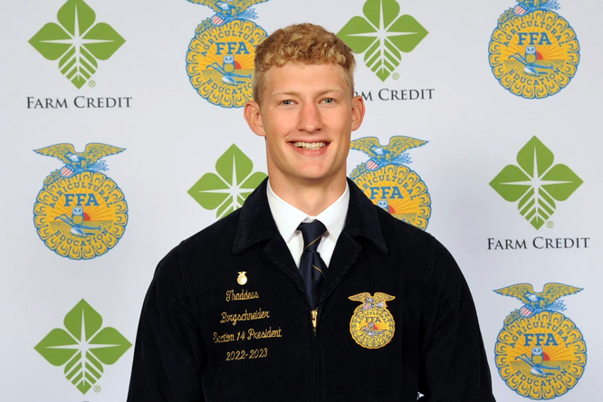 Thaddeus Bergschneider stands in front of a backdrop in official dress.