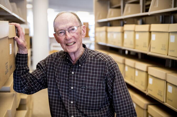 A smiling James F. Evans stands in an archive.