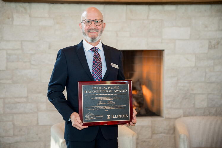 A man in a suit standing in front of a fireplace holding a plaque