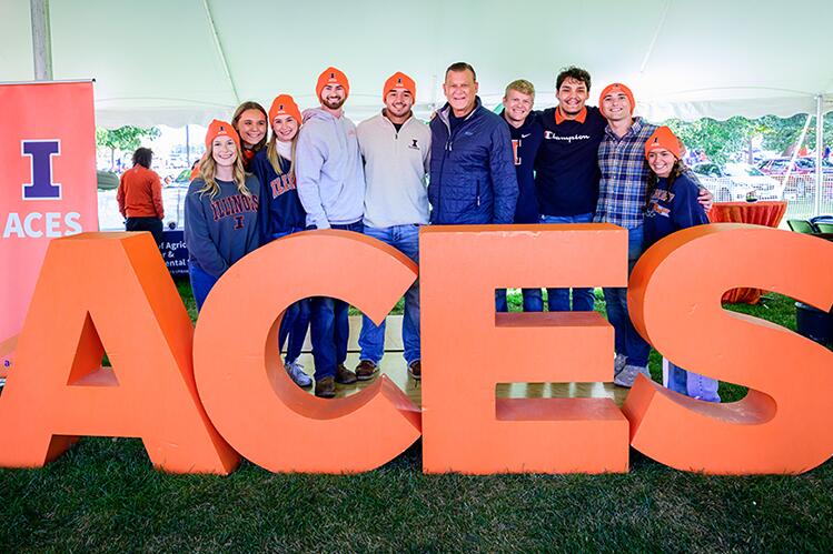 Nine students stand beside coach Underwood behind large orange ACES letters.