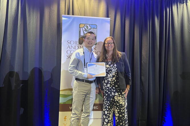 A man holding an award smiles beside a woman