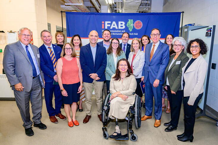 Group photo of people in business attire in front of an iFAB-branded banner.