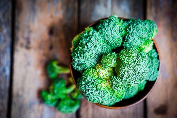 Bowl of broccoli against wood background