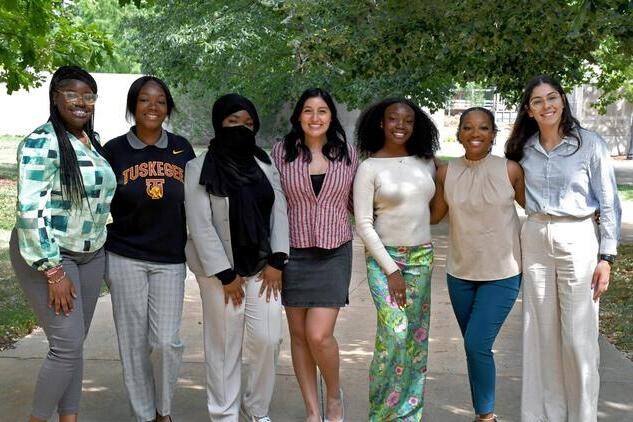 Seven REU participants stand together outdoors.