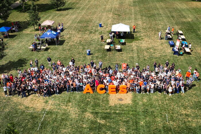 An aerial view of the College of ACES New Student Welcome event, where students, faculty, and staff gathered to celebrate the largest freshman class and record undergraduate enrollment in college history. Aerial view of a large crowd gathered around large orange letters spelling ACES.