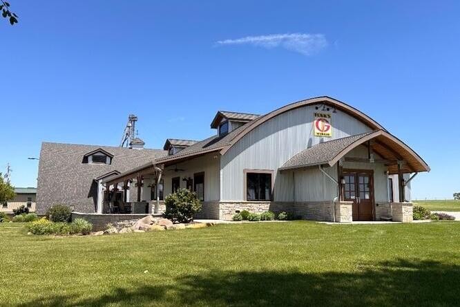 A large, modern farm office building with a curved roof and a “Funk’s G Hybrid” sign under a clear blue sky.