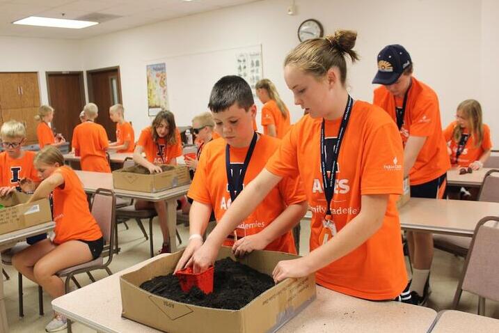 ACES Family Academies students dig through boxes of dirt in classroom